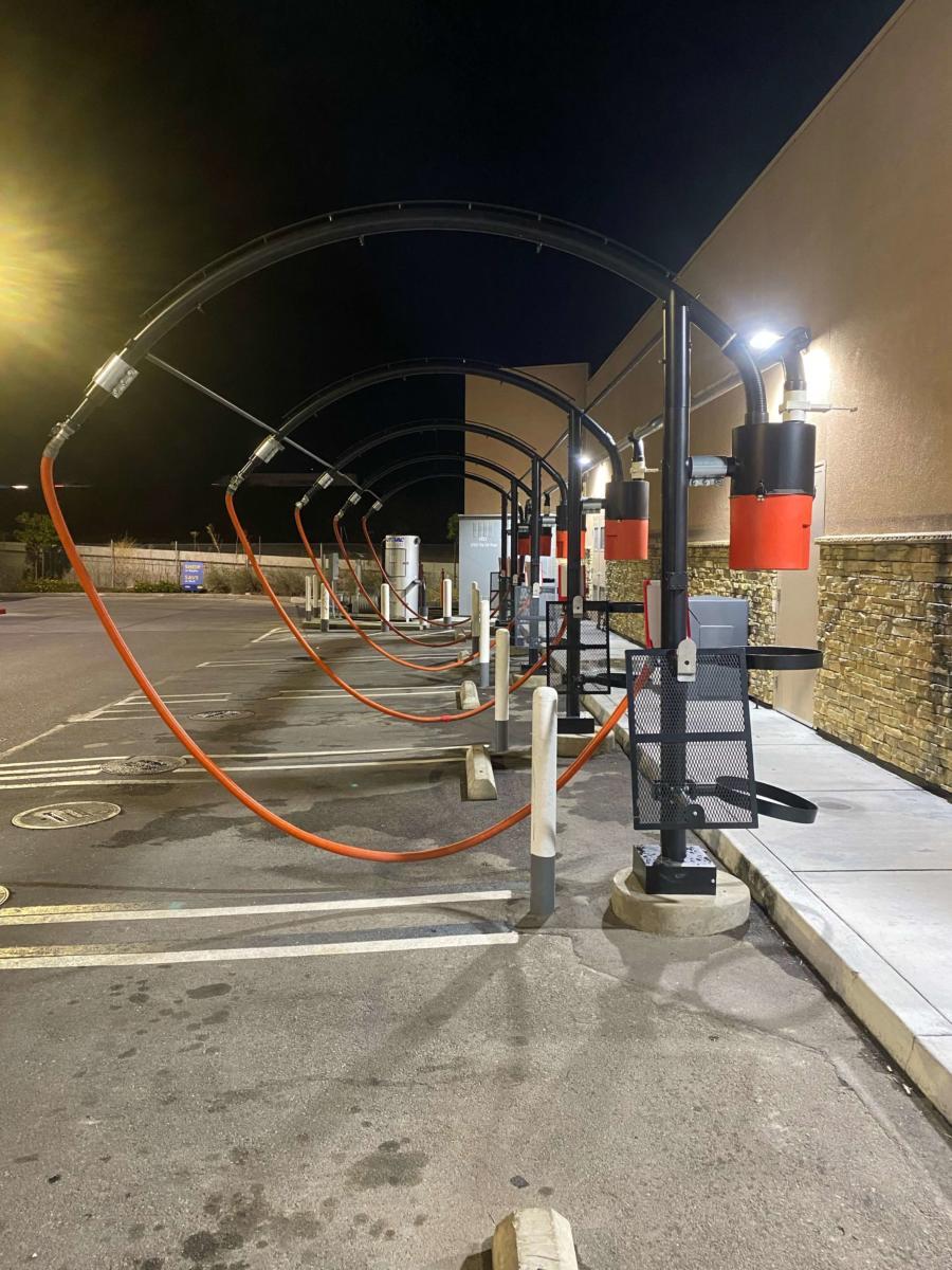 Fueling canopy and conduit routed through a commercial parking lot at dusk