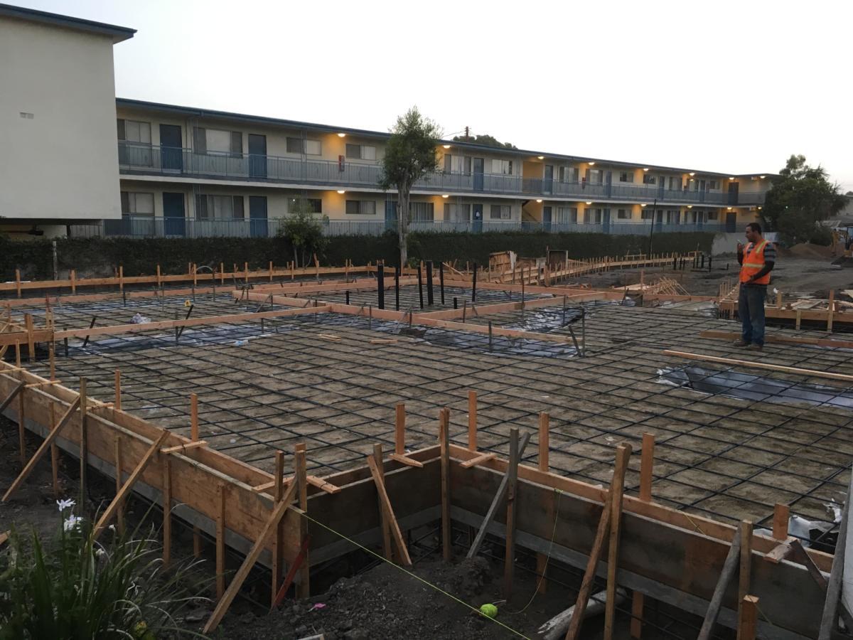 Large rebar grid laid out for a slab-on-grade pour in front of a multi-story building