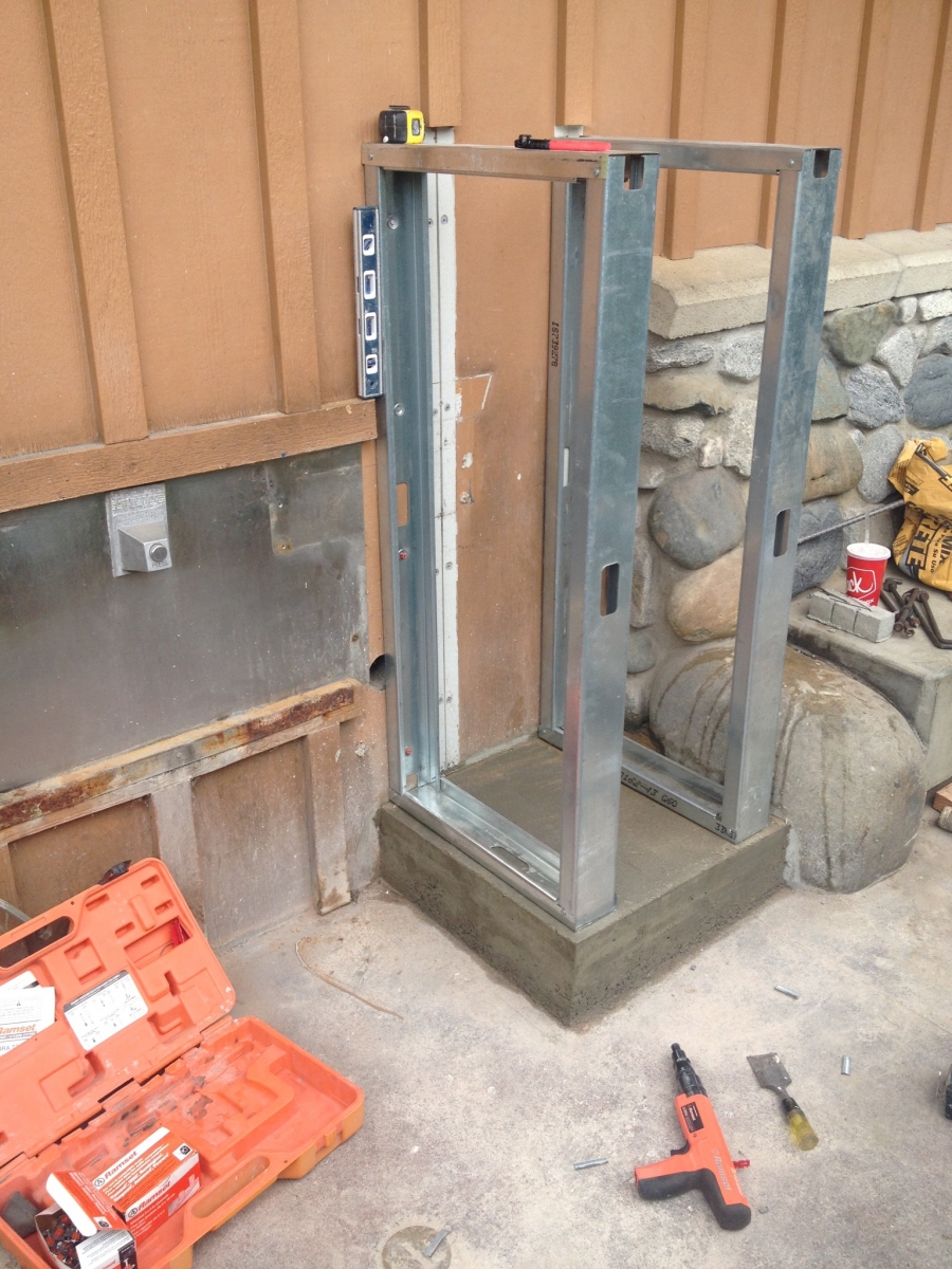 Framed metal equipment enclosure set on a poured concrete pad